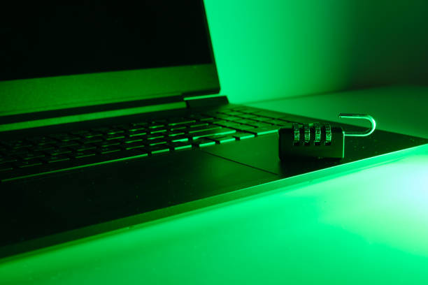 A padlock and a open laptop illuminated with green light. Internet security is essential for online shopping and e-commerce