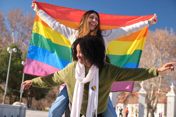 istock Two young women holding rainbow flag and smiling at camera 2194900930