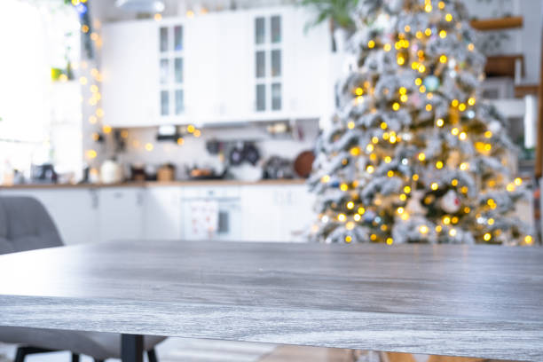 istock Grey Wooden empty table to demonstrate product with space for text with upholstered chairs in white kitchen, modern interior with Christmas tree and fairy lights. New Year, Christmas mood, cozy home. 2194910118