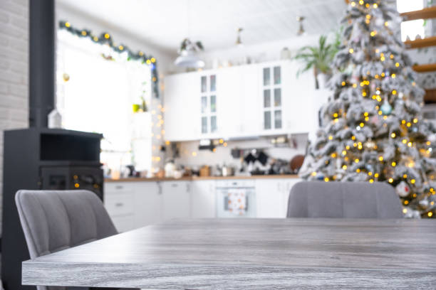 istock Grey Wooden empty table to demonstrate product with space for text with upholstered chairs in white kitchen, modern interior with Christmas tree and fairy lights. New Year, Christmas mood, cozy home. 2194910123