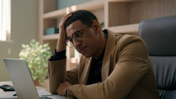 istock Upset stressed African American man negative emotion fail business project with laptop desperate businessman office worker investor take off glasses work crisis bankruptcy worry failure loss finance 2194912567
