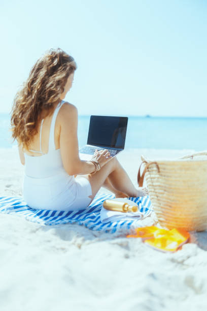 istock Seen from behind modern woman on seacoast with straw bag 2194914031