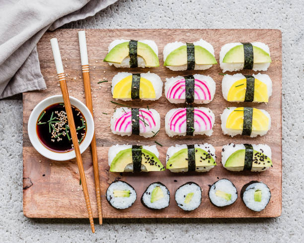 Vegan sushi spread with avocado and colorful beets served on a wooden board with soy sauce