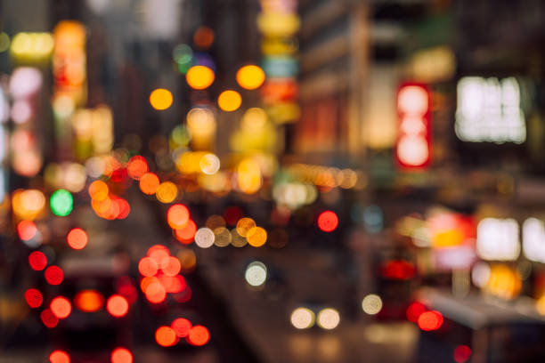 Blurry image of a busy urban street illuminated by vibrant lights and traffic bokeh, evoking the bustling energy of city nightlife.