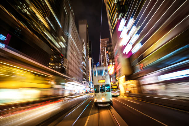 A vibrant tram glides through a lively Asian city center, capturing the dynamic essence of urban night life.