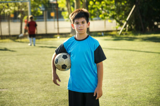 istock Young Boy Holding Soccer Ball on Sunny Field During a Game 2194919028