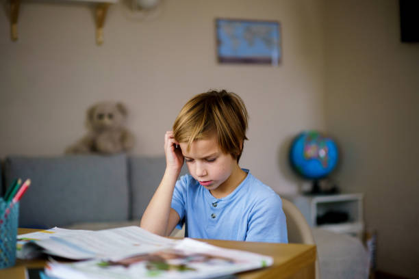 istock Boy reading a book at home 2194921695