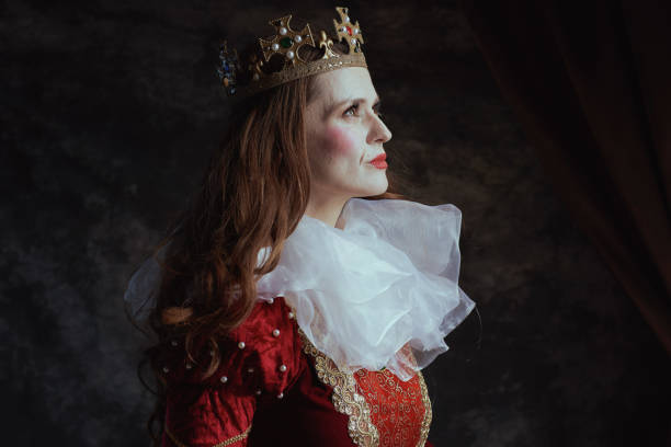 pensive medieval queen in red dress with white collar and crown on dark gray background.