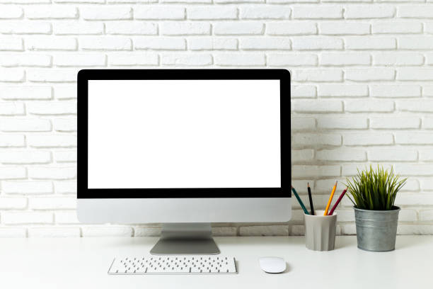 istock Mockup blank screen computer on a wooden desk. desktop empty white screen, with workspace and office supplies on table 2194923172