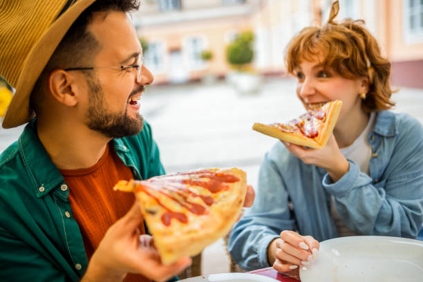 istock Couple in restaurant eats delicious looking pizza with ketchup. 2194930015