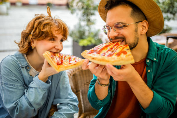 istock Couple in restaurant eats delicious looking pizza with ketchup. 2194930039