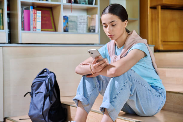 istock Teenage female student using smartphone, inside high school library 2194932695