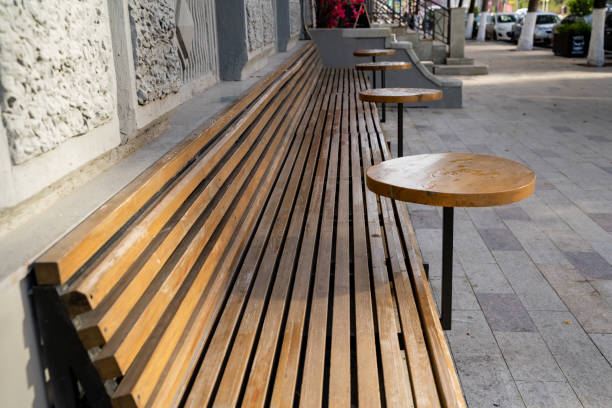 istock This is a sturdy wooden bench, complete with attached tables, situated on a bustling sidewalk. It provides a welcoming presence for passersby to sit and enjoy the vibrant atmosphere 2194932915