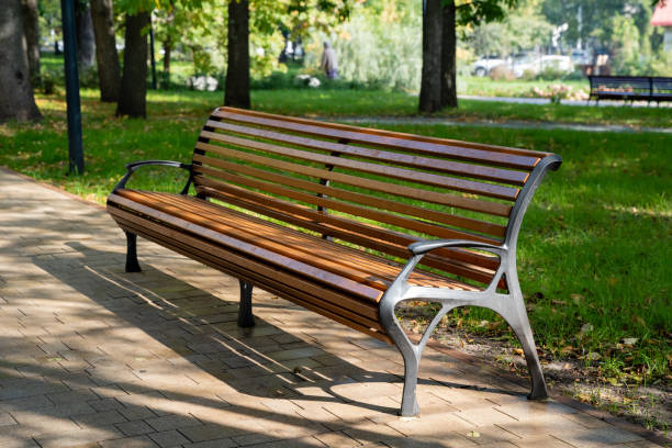 istock In a serene park setting, there is a charming wooden bench that invites visitors to sit and relax, with lush trees providing a beautiful backdrop, enhancing the natural beauty of the scene 2194932938
