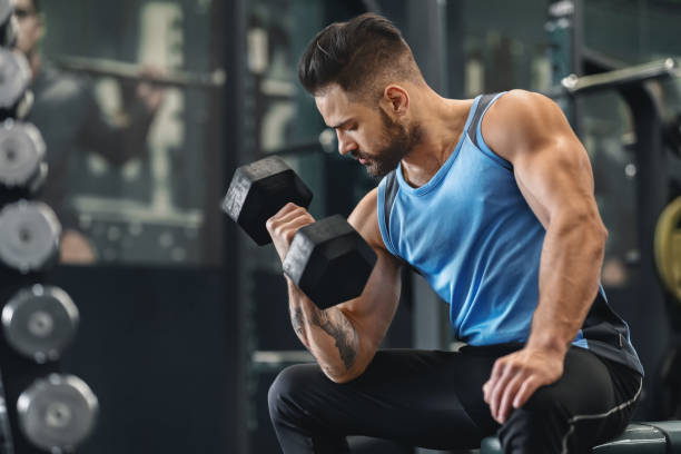 istock Bodybuilder pumping his biceps with dumbbell in gym 2194936957