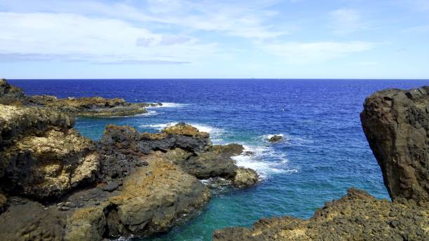 istock Ocean waves crashing against volcanic rocks on a sunny day 2194937795
