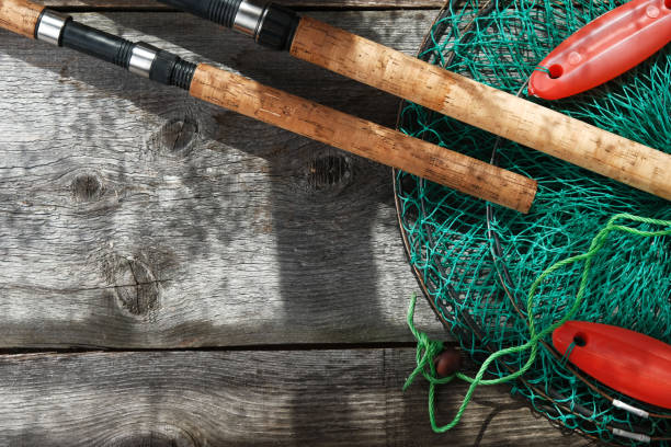 fishing tackle on old vintage wooden background with copy space, flat lay, fishing rod and cage.