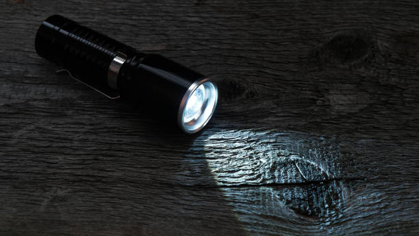 istock Flashlight and a ray of light on a vintage wooden background 2194939018