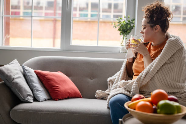 istock Drinking tea on couch, woman wrapped in cozy blanket. 2194940211