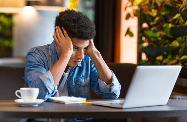 Young Man Experiences Frustration While Studying in a Cozy Cafe During Daytime