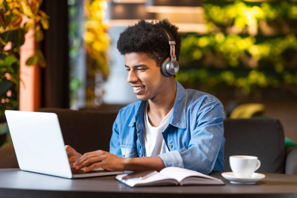 istock Young Man Enjoying Music While Working on Laptop in a Cozy Cafe With Plants 2194941580