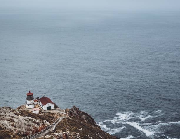 Serene view of coastal landscape featuring rolling waves and distant hills under cloudy skies