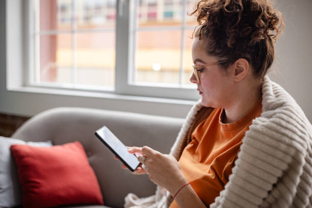istock Woman in blanket using a smartphone on her sofa. 2194944337