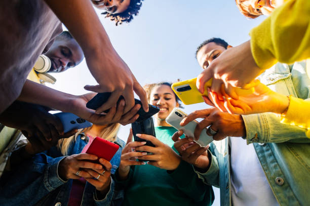 istock Young group of people using mobile phone device standing in circle outdoors 2194946814