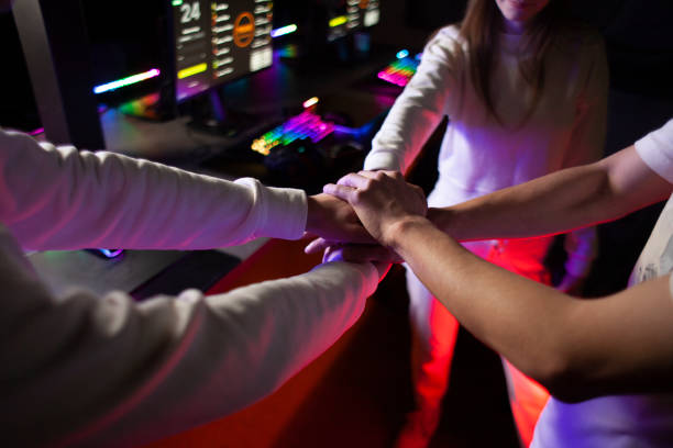 young computer team discussing strategy together and holding hands, team set up before game in computer club, teamwork sign