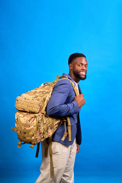 istock Smiling businessman walking with backpack on blue background 2194955259