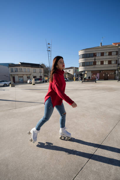 istock Young woman roller skating through city square, sporting red turtleneck and jeans, basking in sunny urban atmosphere 2194959096