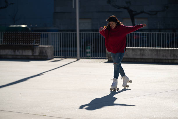 istock Female roller skater spreading arms wide, feeling liberated while gliding through sunny city street, embodying urban recreational freedom and youthful energy 2194959179