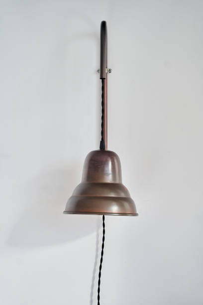 istock A lamp made of copper hangs from a wooden pole on a white wall 2194966203