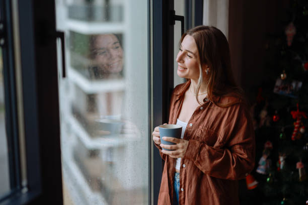 istock Women holding coffee cup while looking away at home 2194969999