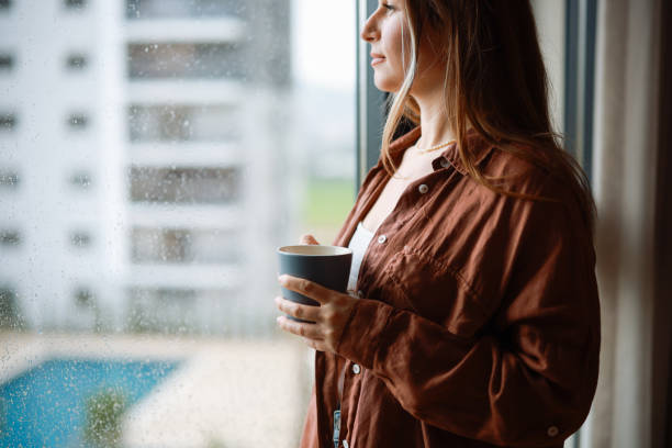 istock Women holding coffee cup while looking away at home 2194970298