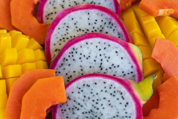 Tropical fruits assortment on a plate, close up. Many colorful ripe tropical fruits background. Mango, papaya and pitahaya