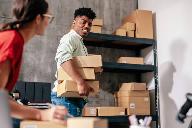 Man carrying boxes in front of colleague