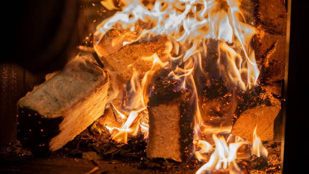 Eco-friendly compressed wood briquettes ignite a warm, inviting fire in a modern stove, showcasing sustainable heating and cozy ambiance for any home