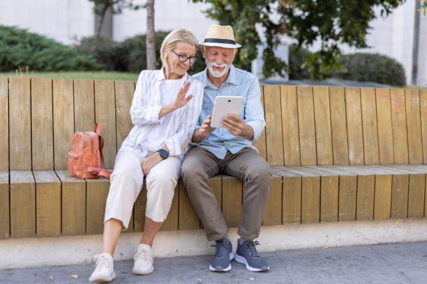 istock Elderly couple cheerfully using a tablet in a sunny outdoor park 2194994170