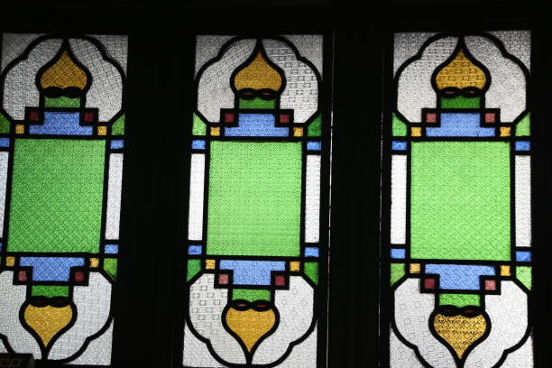 istock A stained glass window with three panels, each panel has an emerald green background and yellow lines on the left side of it 2194997281