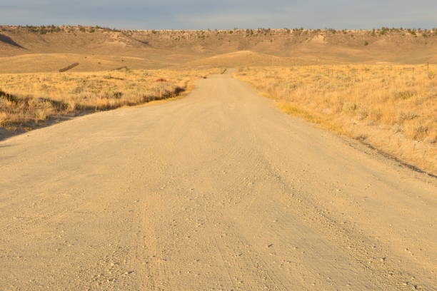 istock Empty Dirt Country Road Against Arid Rolling Landscape and Distant Cliff 2194998315
