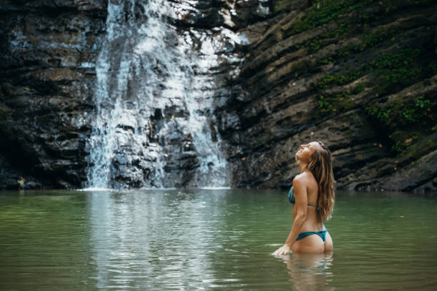 istock Woman in Bikini Standing in Tropical Waterfall Pool 2195000790