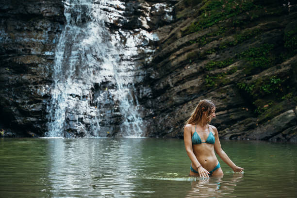 istock Woman Relaxing in Tropical Waterfall Pool in Forest 2195000811