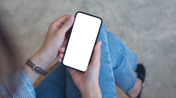 istock Cell phone white blank screen mockup, woman's hand holding mobile phone with blank screen and a cup of coffee in coffee shop, overhead shot, social media marketing design 2195002077