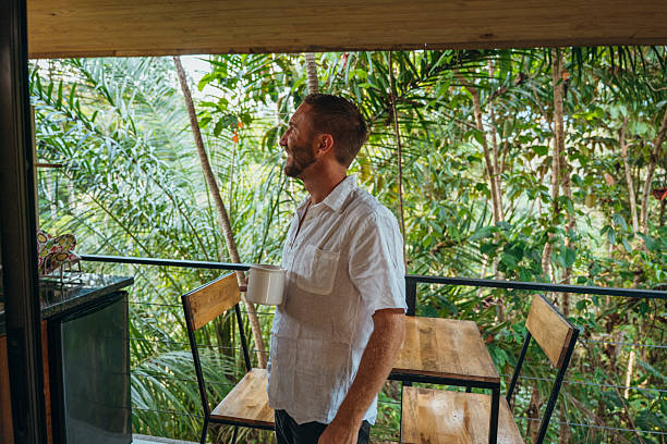 istock Man Enjoying Coffee on Balcony Surrounded by Nature 2195002276