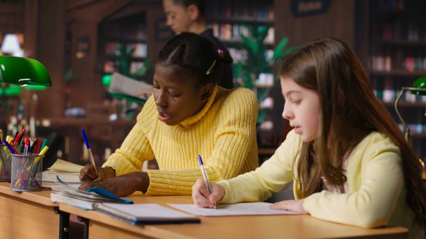 istock Diverse scholars helping each other finish the homework at the library, 2195008676