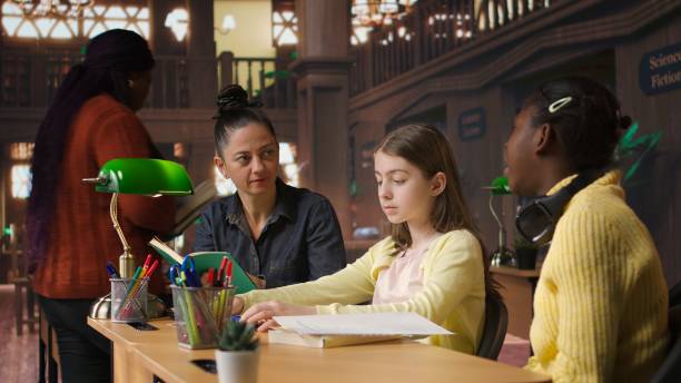 istock Female tutor mentoring schoolgirls in a school library setting 2195010126