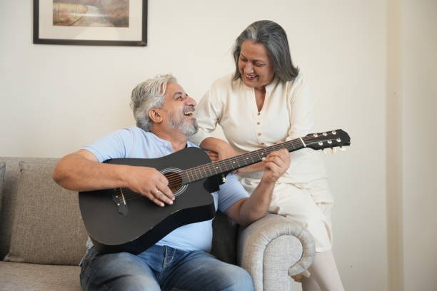 istock senior indian couple enjoying while playing guitar at home. relationship and romance concept. 2195013179