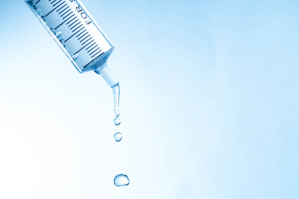 Doctor drawing up Covid-19 vaccine from glass phial bottle and filling syringe injection for vaccination. Close up of hand wearing protective disposable gloves in lab and holding a bottle of vaccination drugs. Hand with blue surgical gloves taking sars-coV-2 vaccine dose from vial with syringe: prevention and immunization concept.