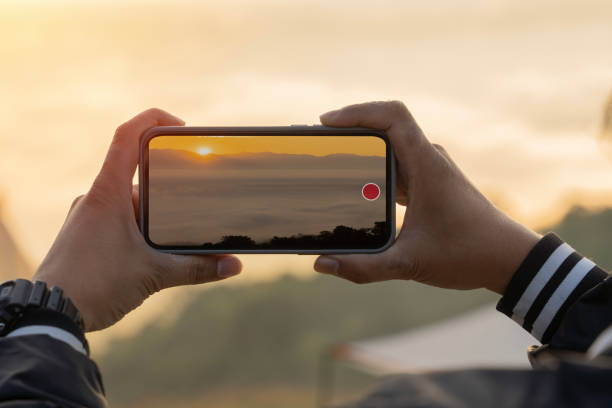 Hands taking photo, recording video on smart phone over real morning mist